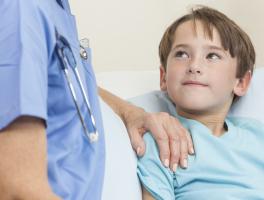 Photo d'un médecin posant sa main sur l'épaule d'un jeune patient allité